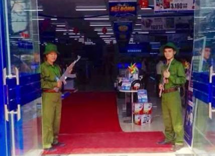 Đôi nam nữ bồng súng chào khách trước cửa siêu thị