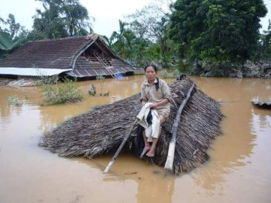 Một người dân lên nóc nhà tránh lũ ở Quảng Bình - Ảnh: Ngọc Hà