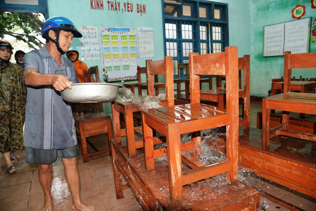 Các thầy cô giáo tranh thủ vệ sinh bàn ghế, đợi nước rút để tiếp tục dạy học trở lại. Ảnh: Tử Trực