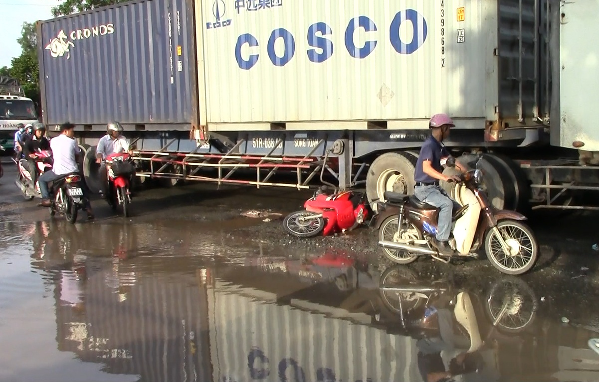 Vấp ổ gà, một phụ nữ suýt chết dưới bánh xe container