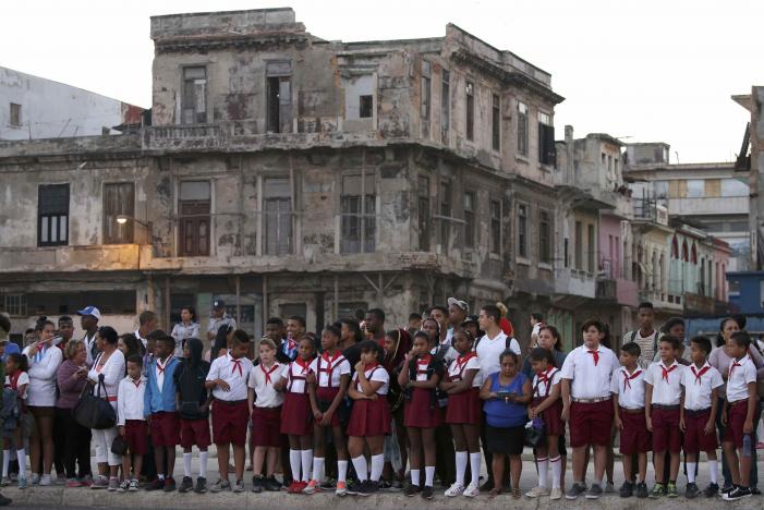 Học sinh đứng bên vệ đường theo dõi đoàn xe. Ảnh: REUTERS