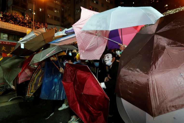 Đ&aacute;m đ&ocirc;ng d&ugrave;ng &ocirc; che chắn. Ảnh: REUTERS