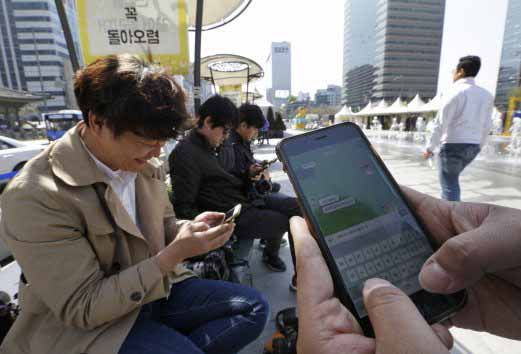 Người đ&agrave;n &ocirc;ng H&agrave;n Quốc (b&ecirc;n phải) đang sử dụng ứng dụng tin nhắn KakaoTalk Ảnh: AP
