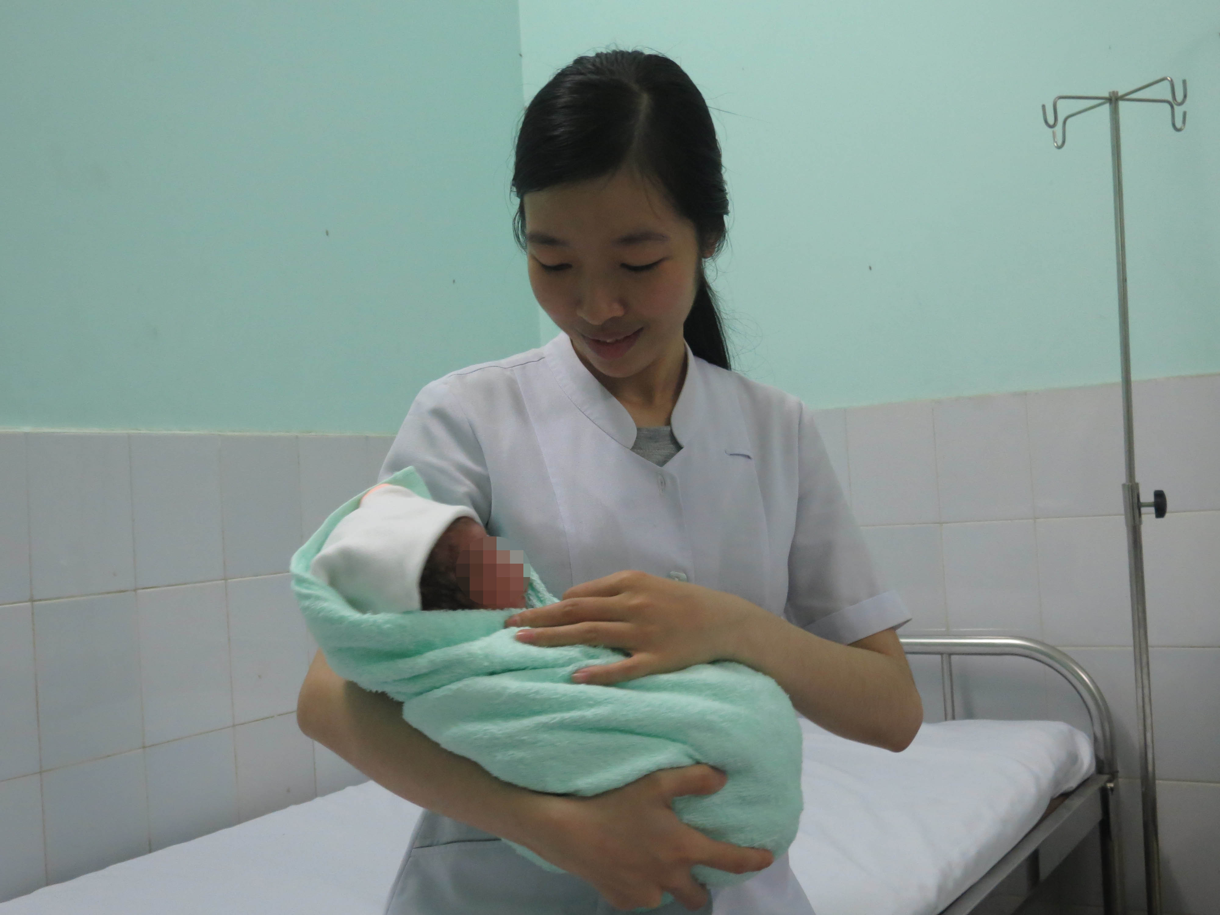 B&eacute; trai mới sinh trong v&ograve;ng tay một nữ hộ sinh của Bệnh viện Quận G&ograve; Vấp