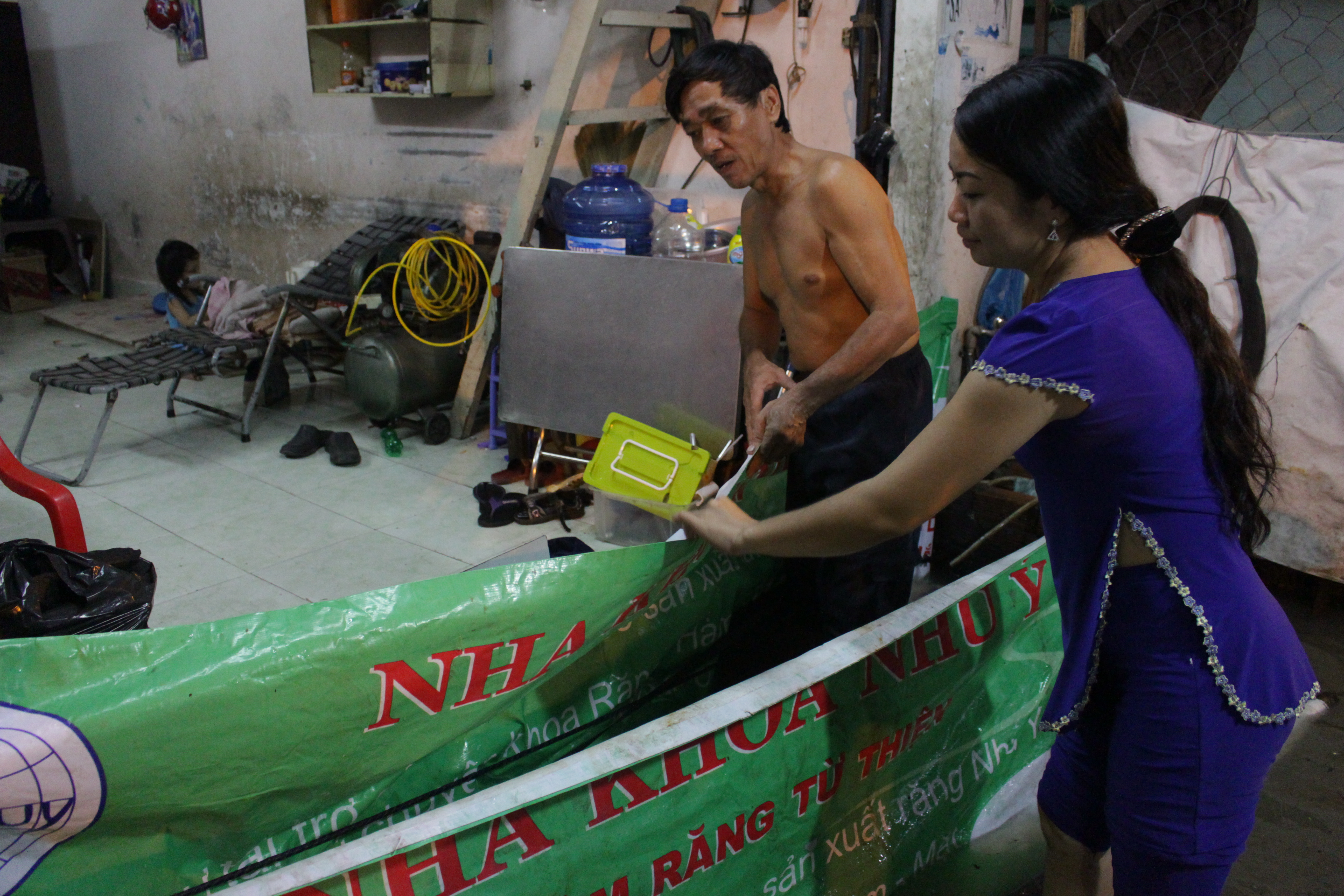 Người dân sử dụng những 2 tấm chắn bằng băng rôn và mica để ngăn nước tràn vào nhà cũng như sóng dạt mạnh mỗi khi xe lớn chạy qua.