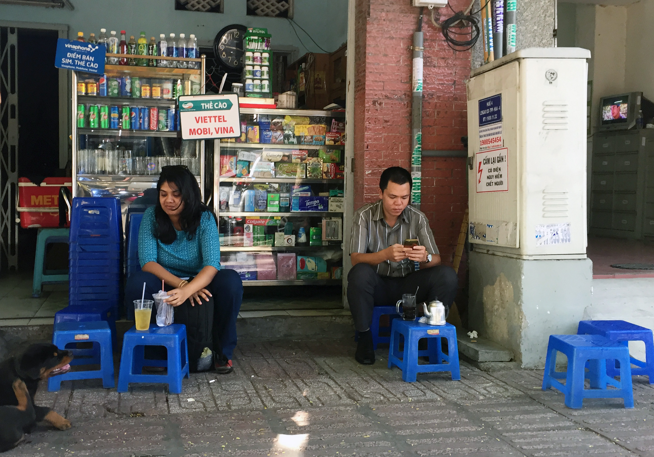 Kh&aacute;ch uống c&agrave; ph&ecirc; v&ocirc; tư ngồi cạnh bốt điện tr&ecirc;n đường Trương Định