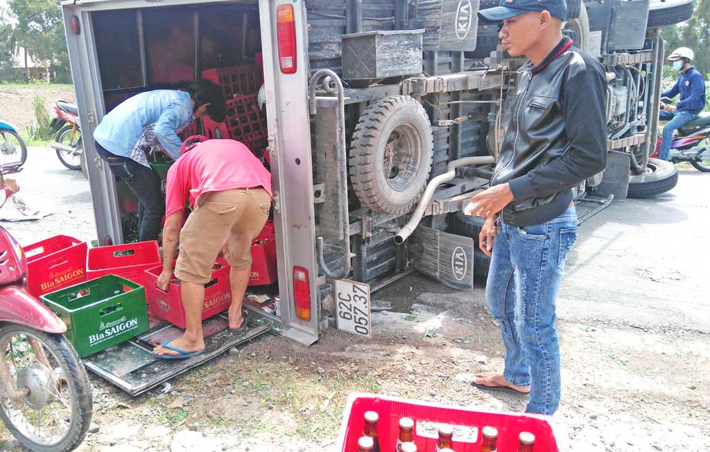 Hàng chục người dân phụ gom bia cho xe tải bị lật