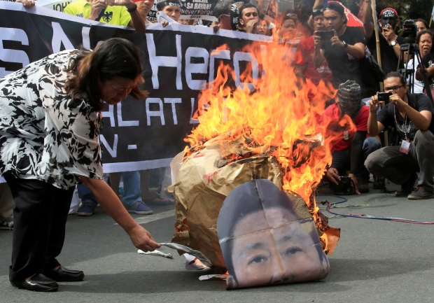 Một người biểu tình đốt hình ông Marcos. Ảnh: Reuters