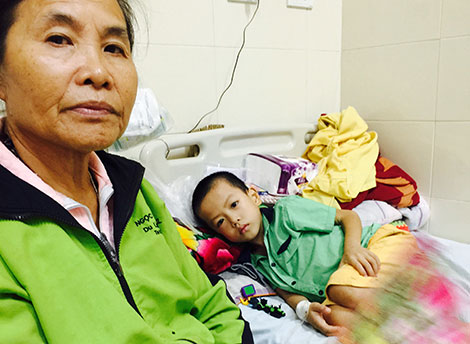 
B&eacute; Nguyễn Đ&igrave;nh Dũng nằm đau đớn tr&ecirc;n giường, b&ecirc;n cạnh l&agrave; b&agrave; nội.
