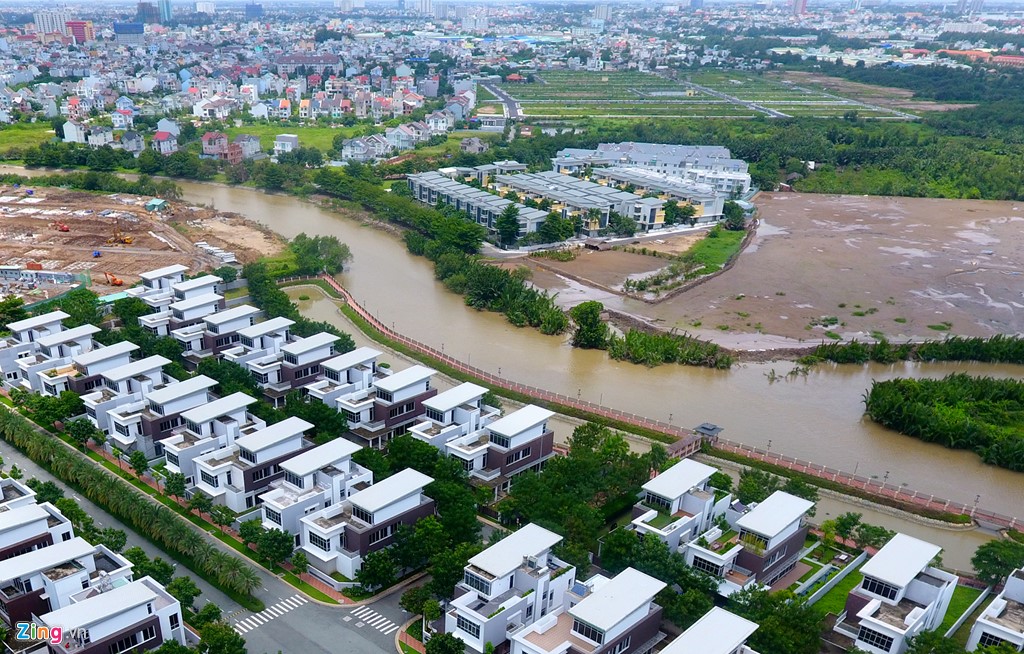 Đối diện b&ecirc;n kia s&ocirc;ng l&agrave; một khu biệt thự nhỏ liền kế mọc tr&ecirc;n v&ugrave;ng đầm lầy.