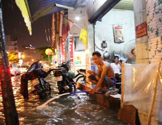 
Một hộ d&acirc;n phải d&ugrave;ng v&ograve;i bơm nước ra ngo&agrave;i do bị tr&agrave;n v&agrave;o nh&agrave;
