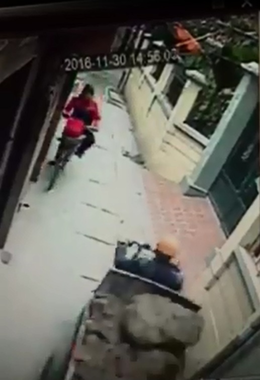 
Người phụ nữ đạp xe, chở b&eacute; trai ph&iacute;a sau đi trong ng&otilde; hẹp. Ảnh cắt từ video
