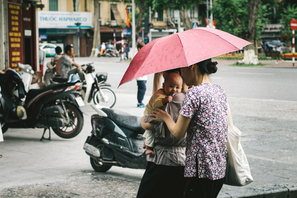 Em bé dường như lần đầu tiên thấy mưa nên có chút rụt rè, e ngại. Dù đã được bế trên tay nhưng vẫn bám chặt lấy mẹ.