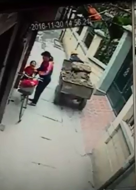 
Sau vụ tai nạn, người phụ nữ bế b&eacute; trai l&ecirc;n y&ecirc;n xe đạp. Ảnh cắt từ video
