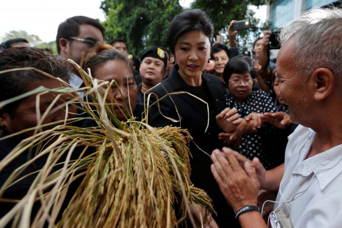 Bà Yingluck trong vòng vây người ủng hộ khi bà đến tòa án tối cao ở Bangkok hôm 4-11. Nhiều người cầm theo lúa hoặc tờ tiền 20 baht. Ảnh: Reuters