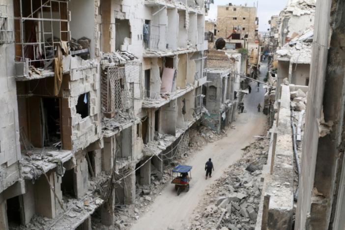 Người dân di chuyển bên những căn nhà bị tàn phá ở Aleppo ngày 5-5-2016. Ảnh: Reuters