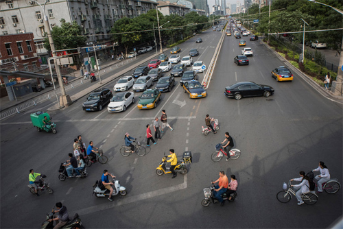 Ôtô riêng, taxi, xe đạp, xe điện và người đi bộ tại một điểm giao cắt ở thủ đô Bắc Kinh hồi tháng 5. Ảnh: New York Times.