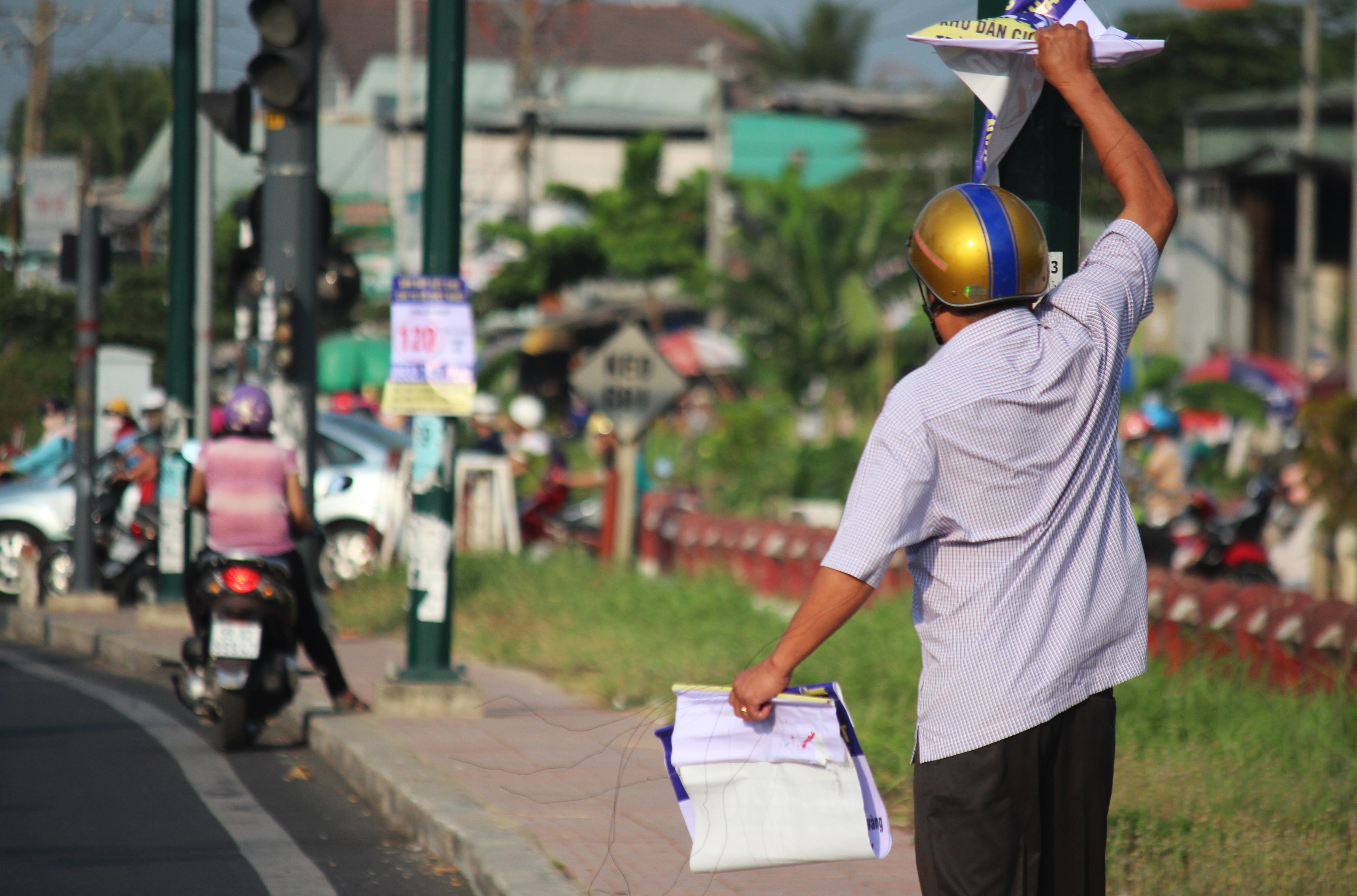 Một cán bộ phường đang cố gắng tháo gỡ các băng rôn trên đường Phạm Văn Đồng (phường Hiệp Bình Chánh, quận Thủ Đức). Vị này cho biết mỗi ngày phải đi tháo gỡ 2-3 lần nhưng vẫn không xuể