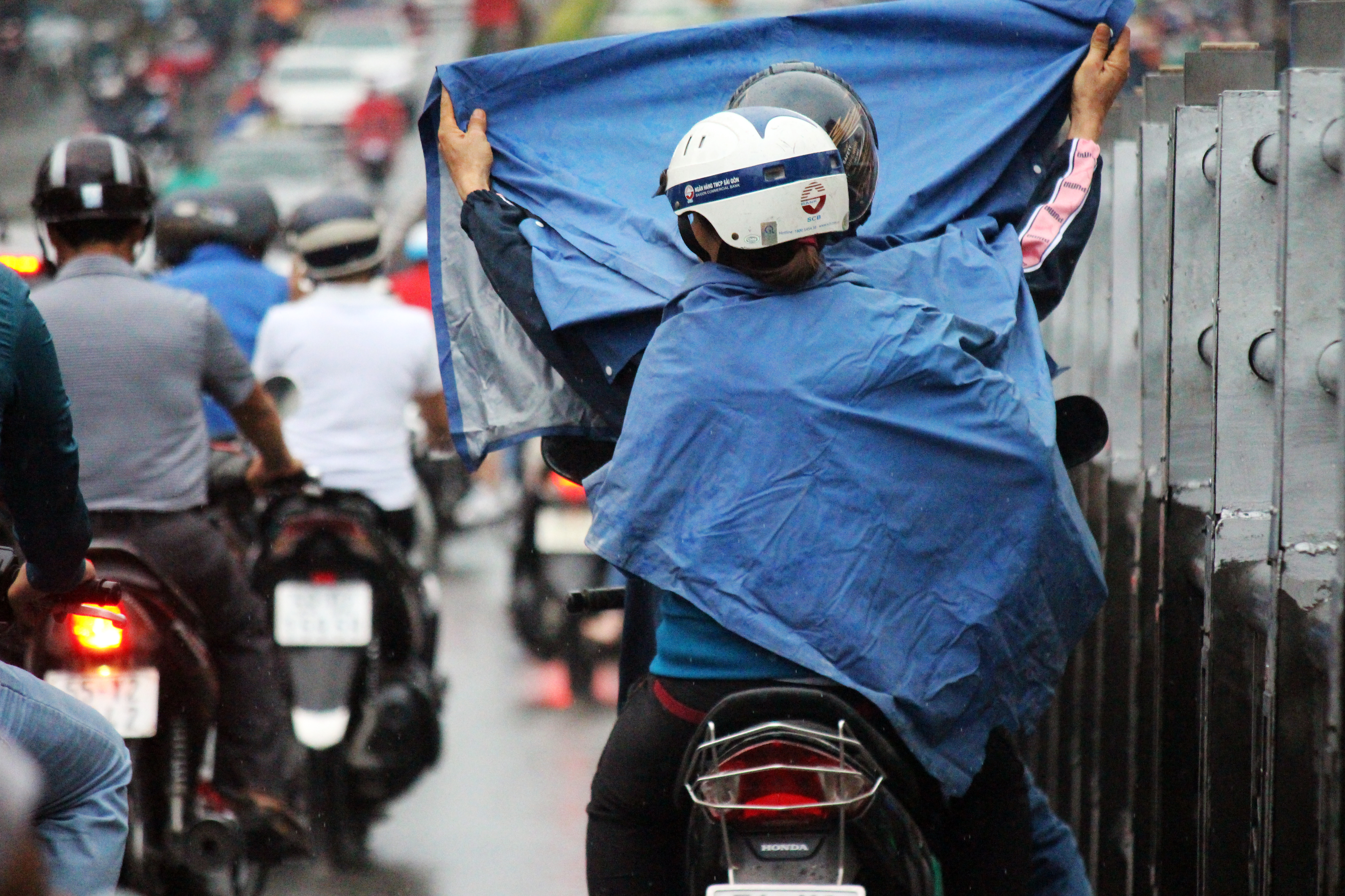 
Người đi xe m&aacute;y dừng tr&ecirc;n cầu vượt Ho&agrave;ng Hoa Th&aacute;m để mặc &aacute;o mưa, cản trở giao th&ocirc;ng, g&oacute;p phần khiến gia tăng &ugrave;n ứ.
