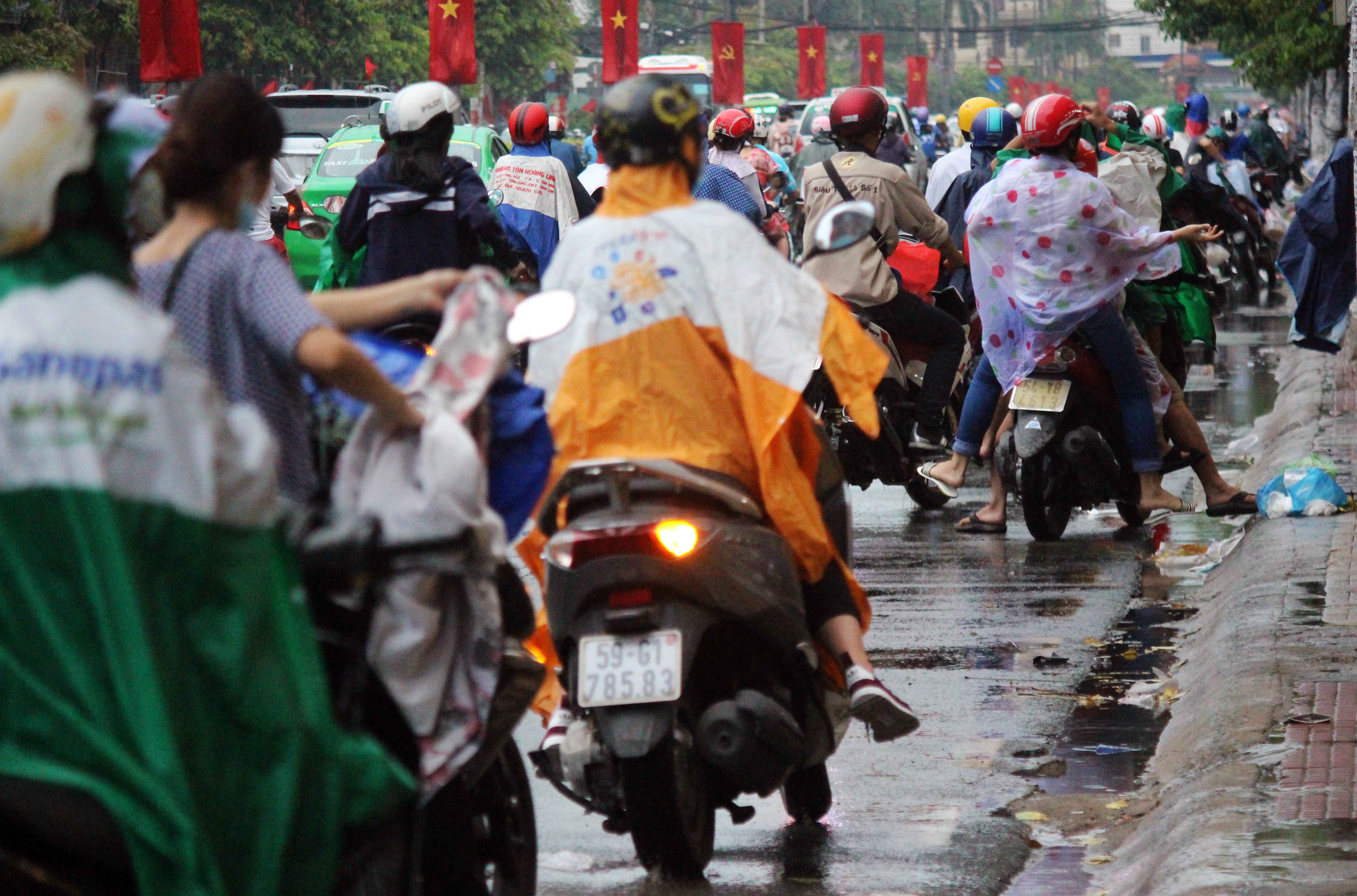 
Khoảng 17 giờ ng&agrave;y 2-5, một cơn mưa bất ngờ tr&uacute;t xuống khiến người d&acirc;n chật vật chạy mưa. Trong ảnh: Nhiều người dừng lại b&ecirc;n đường Cộng H&ograve;a để mặc &aacute;o mưa.
