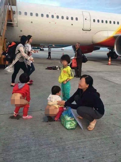 Người phụ nữ tươi cười khi cho các cháu nhỏ tè bậy ở sân bay Ảnh: FACEBOOK