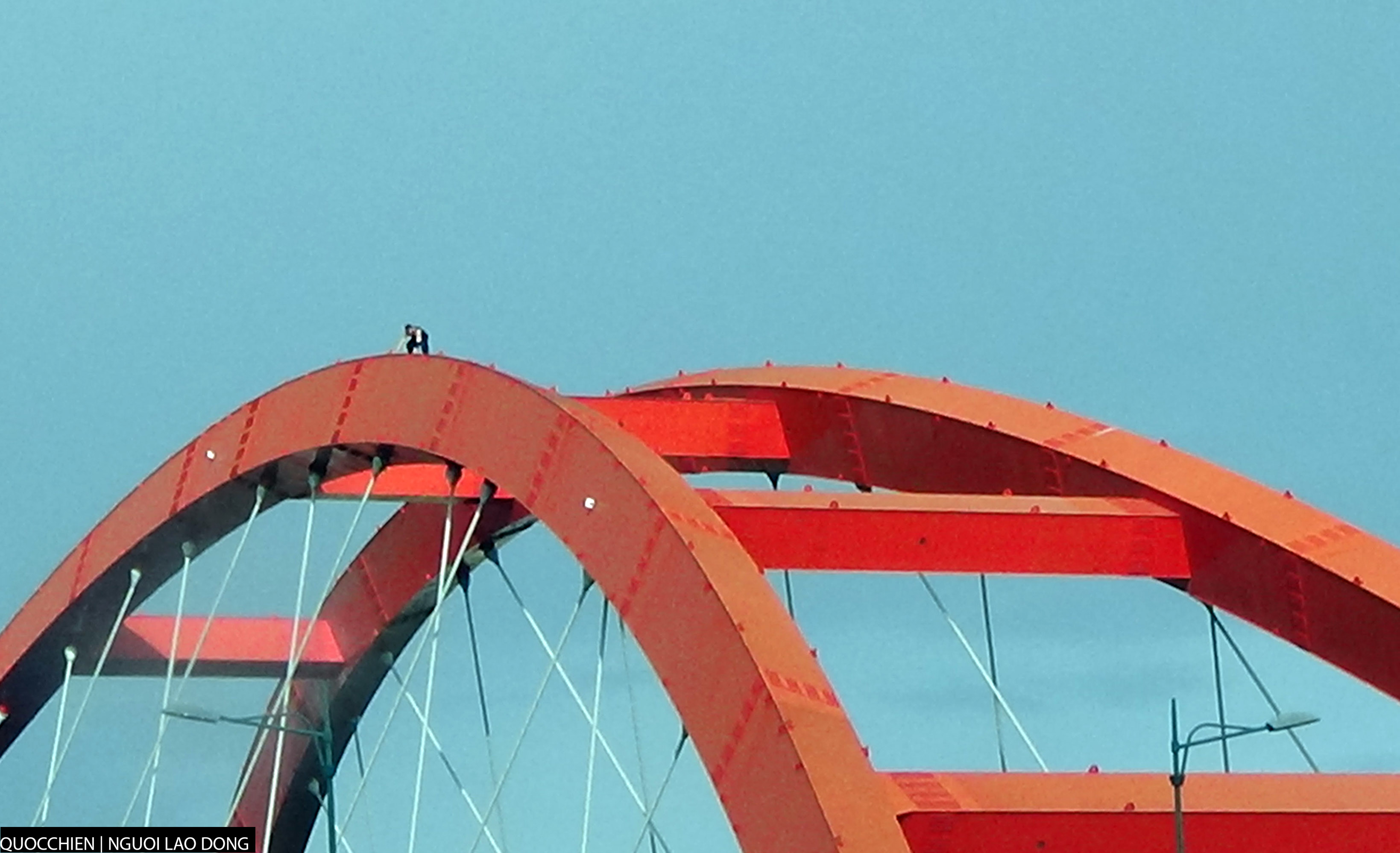Nam thanh niên cố gắng bám vào nóc cầu vì gió thổi mạnh.