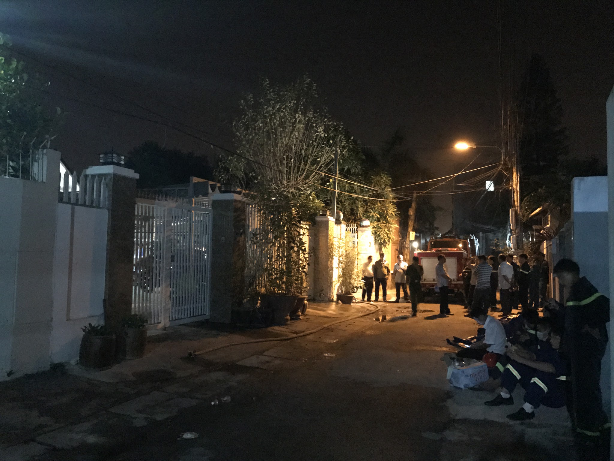 Lực lượng chức năng đứng trước căn nhà nơi xảy ra vụ cháy lúc rạng sáng