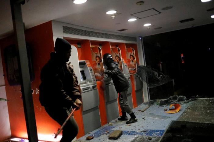 Người biểu tình đập phá ATM. Ảnh: Reuters