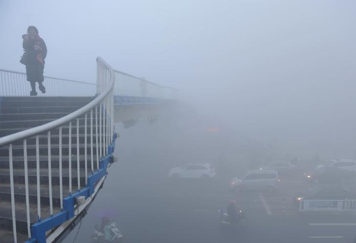Một người đi bộ trong khói bụi ở TP Phụ Dương, tỉnh An Huy ngày 3-1. Ảnh: Reuters