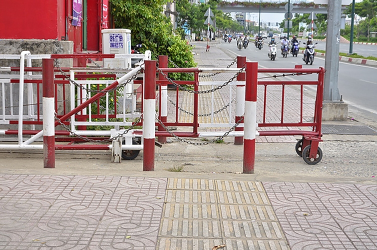Nhân viên gác chắn đường sắt không đẩy hết rào chắn vào trong mà vẫn để lấn vỉa hè