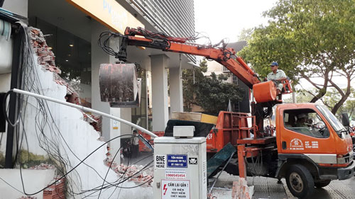 Lực lượng chức năng tháo dỡ bức tường cao 4 m trước Công ty Hoa tiêu hàng hải Khu vực 1 (đường Đinh Tiên Hoàng, phường Bến Nghé, quận 1, TP HCM) sáng 6-3 Ảnh: SỸ ĐÔNG