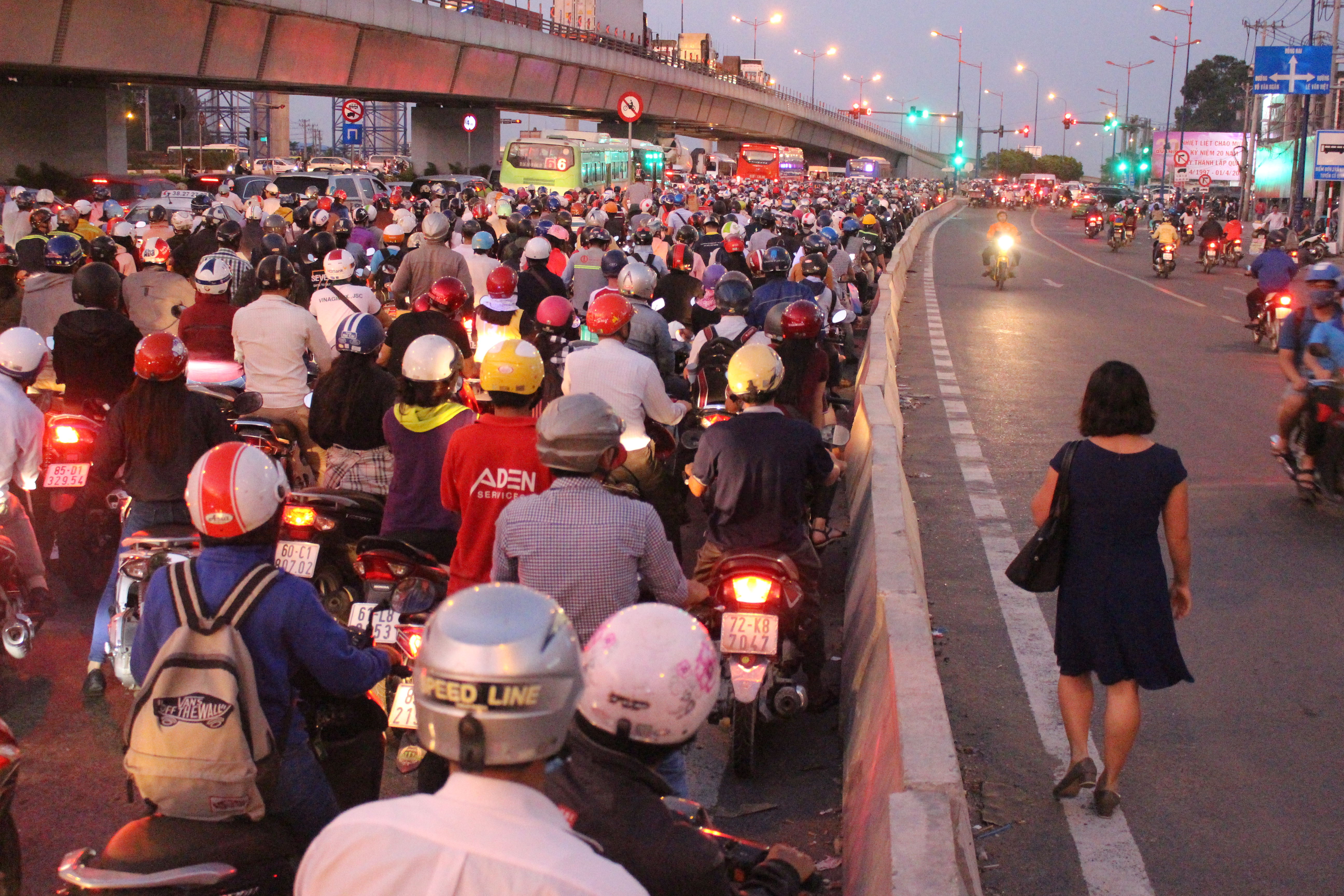 Một người phụ nữ quyết định rời xe m&aacute;y, đi bộ chờ người th&acirc;n ở b&ecirc;n kia ng&atilde; tư.