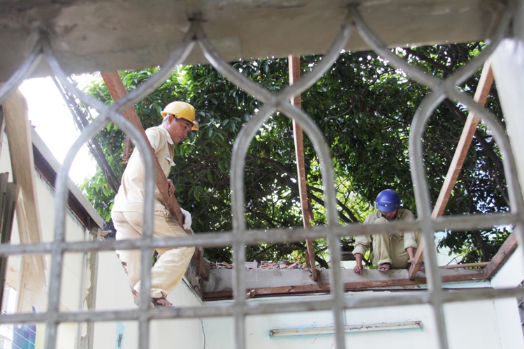 Công nhân tháo xong phần mái và bắt đầu tháo dỡ xà gỗ