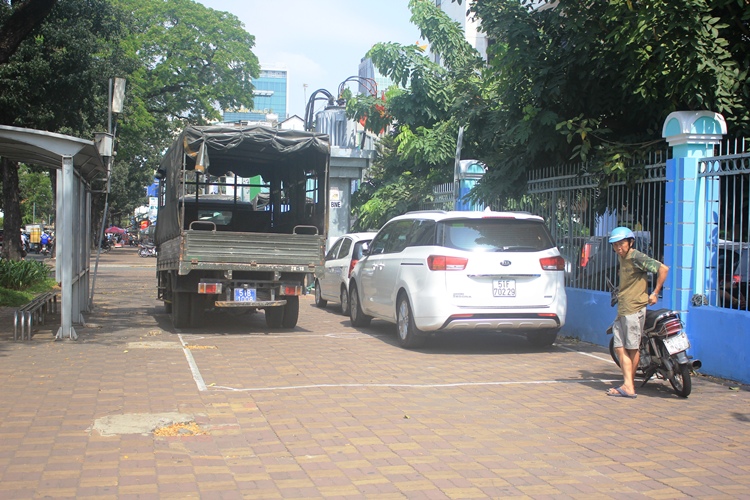 Xe biển xanh của lực lượng vũ trang quận 1 cùng xe biển trắng đậu trên vỉa hè đường Đinh Tiên Hoàng