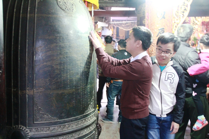 
Nhiều du kh&aacute;ch đ&atilde; tranh thủ v&agrave;o trong đền sờ v&agrave;o chu&ocirc;ng đồng để xin may mắn
