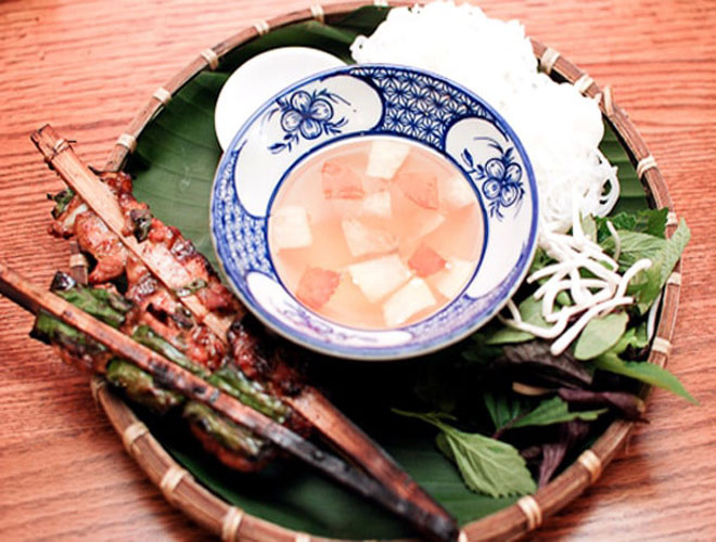 
Ng&otilde; chợ Đồng Xu&acirc;n l&agrave; một trong số &iacute;t nơi b&aacute;n chả que tre ở H&agrave; Nội. M&oacute;n b&uacute;n chả ở đ&acirc;y được l&agrave;m theo phong c&aacute;ch cổ truyền: chả bọc l&aacute; lốt, kẹp que tre nướng tr&ecirc;n than hoa. Thịt lợn ngọt quyện với vị thơm của l&aacute; lốt, h&agrave;nh phi v&agrave; m&ugrave;i d&acirc;n d&atilde; của tre &aacute;m kh&oacute;i. Ngo&agrave;i ra, điểm độc đ&aacute;o nữa của qu&aacute;n l&agrave; b&uacute;n chả ở đ&acirc;y được ăn với giấm me, giấm sấu n&ecirc;n c&oacute; vị kh&aacute;c biệt hẳn. Với 35.000 đồng, bạn đ&atilde; c&oacute; ngay một b&aacute;t b&uacute;n chả đầy đặn b&uacute;n với 2 que chả miếng, 2 que chả băm l&aacute; lốt. Ảnh: Blogphuot.vn.
