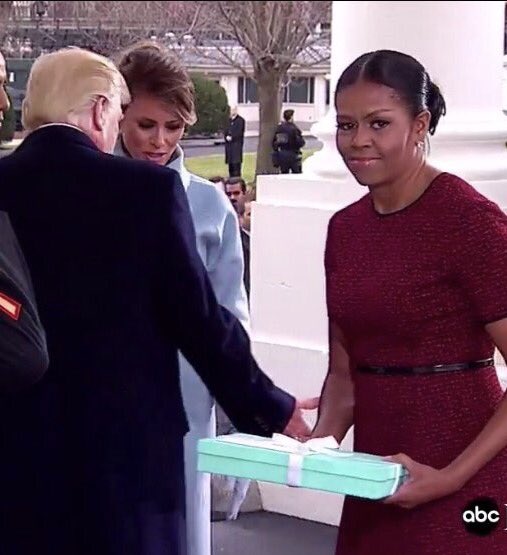 Khuôn mặt lúng túng của bà Obama khi nhận món quà mà bà Trump mang đến Nhà Trắng. Tạm thời bà không biết phải cất nó đi đâu. Ảnh: ABC