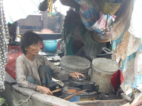 
B&agrave; Hai cặm cụi nấu ăn trong chiếc thuyền mục ruỗng.
