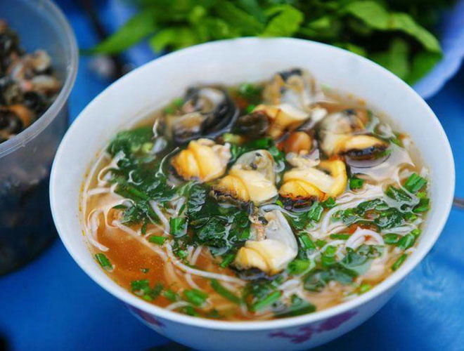 
Nằm ở cuối của ng&otilde; chợ c&oacute; một h&agrave;ng b&uacute;n tuy nhỏ nhưng tấp nập kh&aacute;ch ra v&agrave;o, cao điểm v&agrave;o buổi trưa. Ở đ&acirc;y c&oacute; 2 loại l&agrave; b&uacute;n ri&ecirc;u ốc v&agrave; b&uacute;n ốc chuối đậu. B&uacute;n ri&ecirc;u ốc ngon nhất l&agrave; phần nước d&ugrave;ng. Nước chua chua, thơm nhẹ nh&agrave;ng vị giấm bỗng. Ốc b&eacute;o ngậy, gi&ograve;n v&agrave; kh&ocirc;ng bị dai như nhiều h&agrave;ng b&uacute;n ốc kh&aacute;c. B&aacute;t kh&ocirc;ng c&oacute; th&ecirc;m gi&ograve;, chả hay thịt b&ograve; như xu hướng b&acirc;y giờ. C&ograve;n b&uacute;n ốc chuối đậu thường được ăn kh&ocirc;. B&aacute;t b&uacute;n thơm ngon với m&agrave;u v&agrave;ng tươi của nghệ, b&ugrave;i của miếng chuối nấu đến độ ch&iacute;n tới, kh&ocirc;ng bị n&aacute;t, đậu phụ r&aacute;n v&agrave;ng, thơm gi&ograve;n. Gi&aacute; của một b&aacute;t b&uacute;n ốc l&agrave; 30.000 đến 35.000 đồng. Ảnh: Chiến Trần
