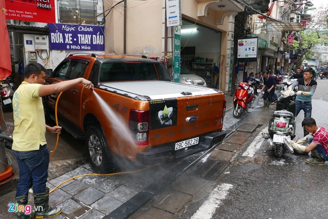 Trên phố Nhà Hoả, ôtô, xe máy tấp nập nối đuôi nhau vào làm sạch. Giá rửa xe máy 50.000 đồng, ôtô 200.000 đồng/chiếc