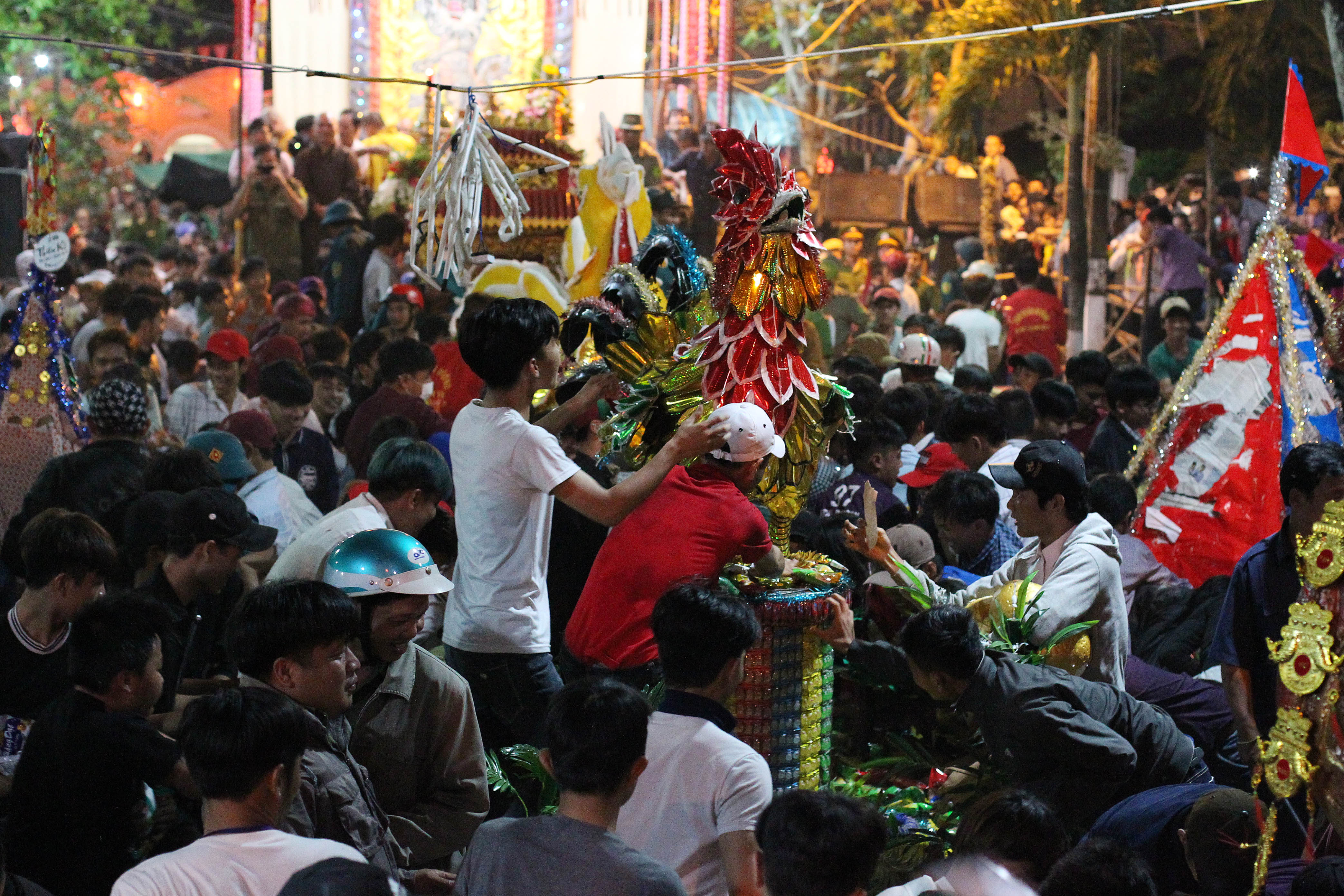 
B&aacute;nh c&uacute;ng tr&ecirc;n gi&agrave;n th&iacute; thực được quăng ra, c&aacute;c cỗ b&aacute;nh được rất nhiều người v&acirc;y quanh.

