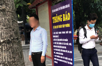 Người đàn ông không đeo khẩu trang "tạo dáng" chụp ảnh cạnh biển thông báo chống dịch Covid-19