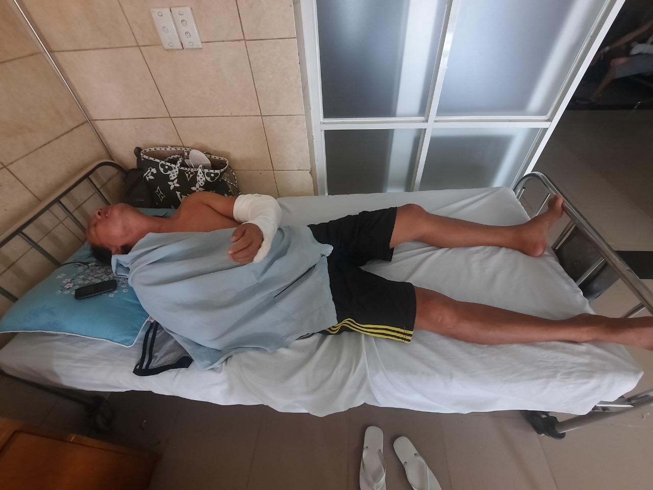 Đang ngồi trước cửa nhà, bị kề mã tấu vào cổ, chém gây thương tích