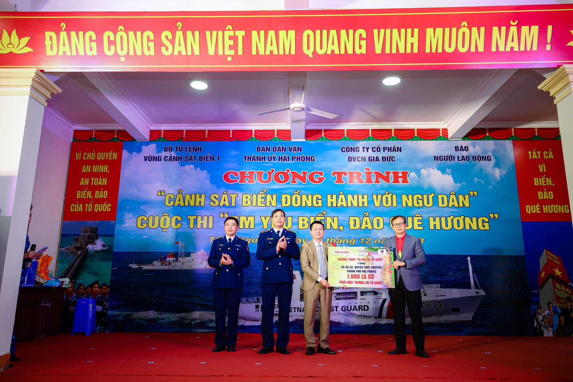 Ông Phạm Hồng Kỳ - Ủy viên Ban Biên tập, Trưởng Văn phòng Đại diện Báo Người Lao Động khu vực miền Bắc (bìa phải) - trao bảng tượng trưng 1.000 lá cờ Tổ quốc cho đại diện xã An LưẢnh: Hữu Hưng