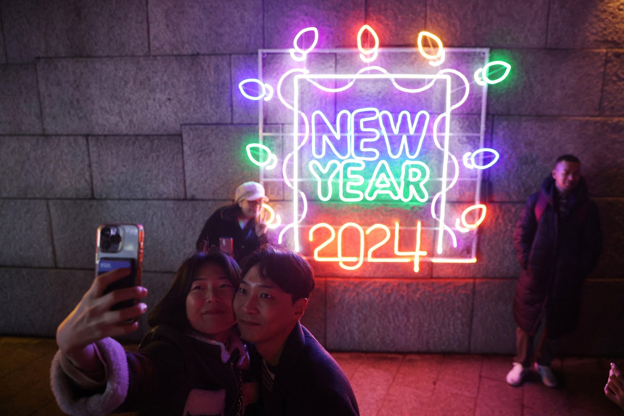 Một cặp đ&ocirc;i chụp ảnh selfie khi c&ugrave;ng nhau ra phố ch&agrave;o đ&oacute;n năm mới 2024 ở Seoul - H&agrave;n Quốc - Ảnh: REUTERS