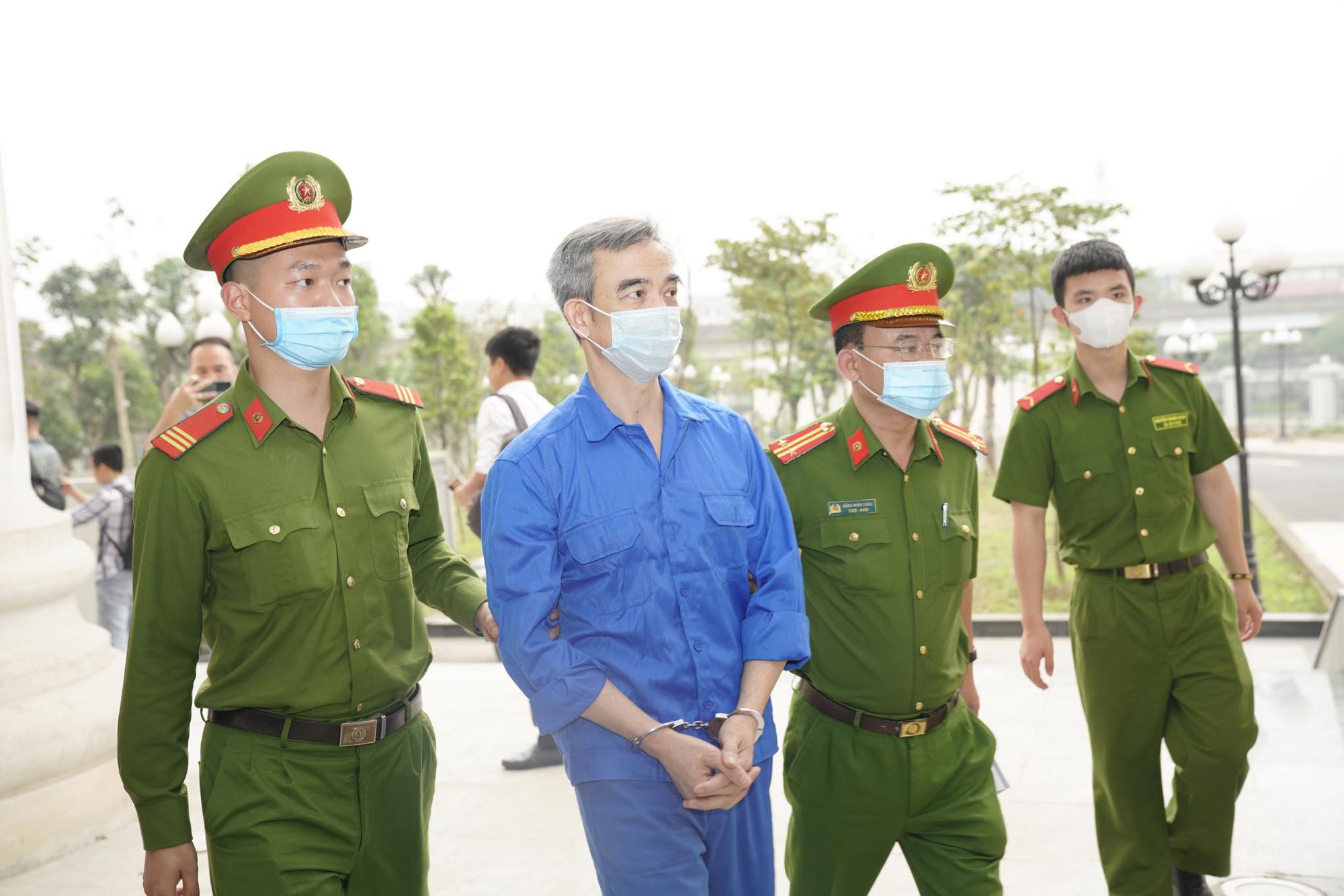 Cựu giám đốc BV Tim Hà Nội Nguyễn Quang Tuấn mặc áo xanh tới tòa trên xe đặc chủng