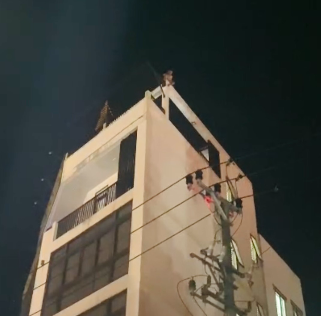 Một người có biểu hiện mất kiểm soát ngồi trên nóc tòa nhà 4 tầng