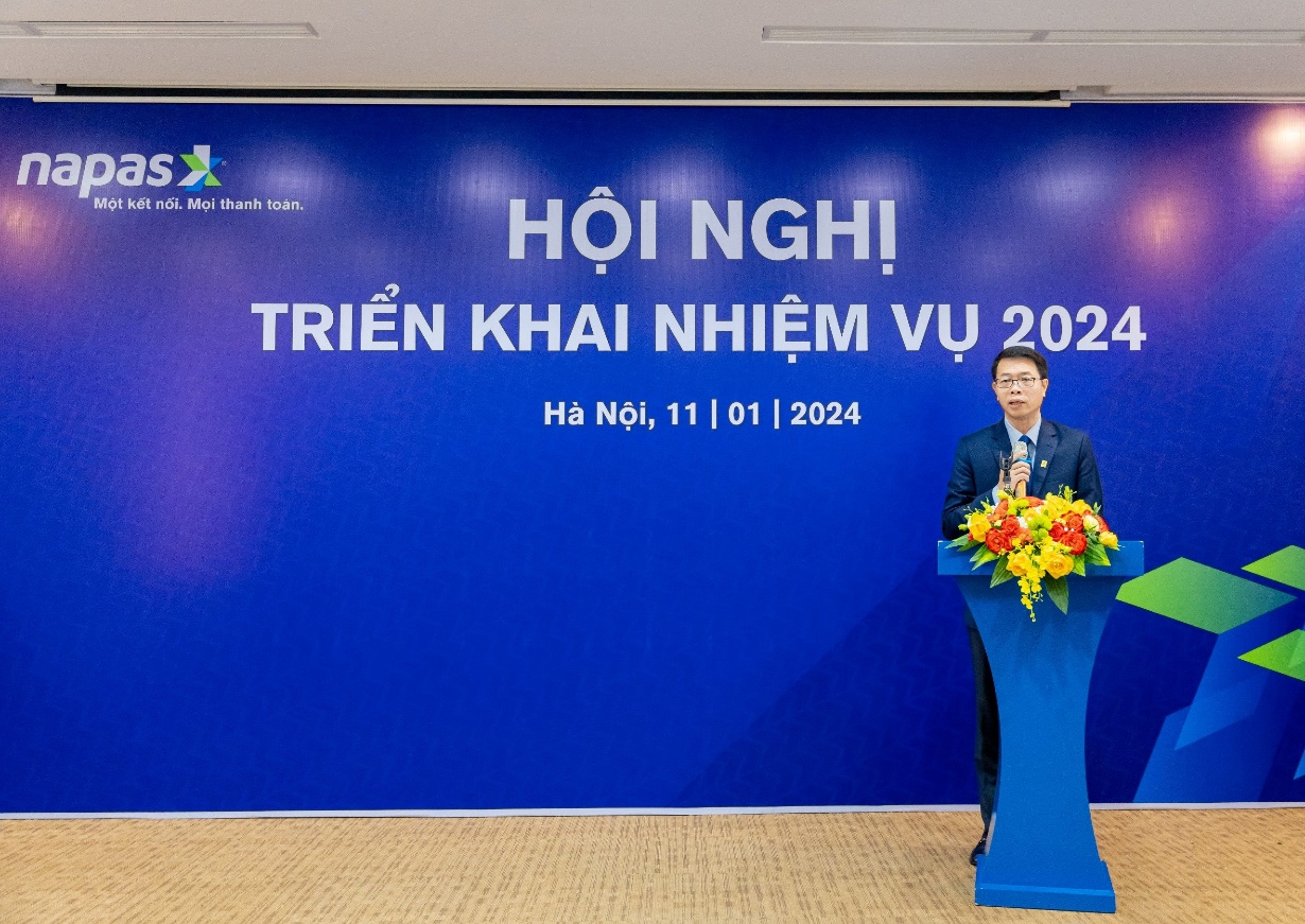 A person standing at a podium with flowers  Description automatically generated