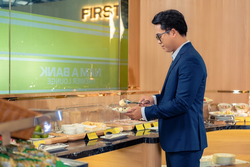 A person in a suit holding food in a glass case Description automatically generated