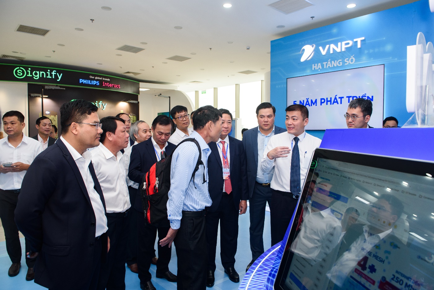 A group of people standing around a computer Description automatically generated